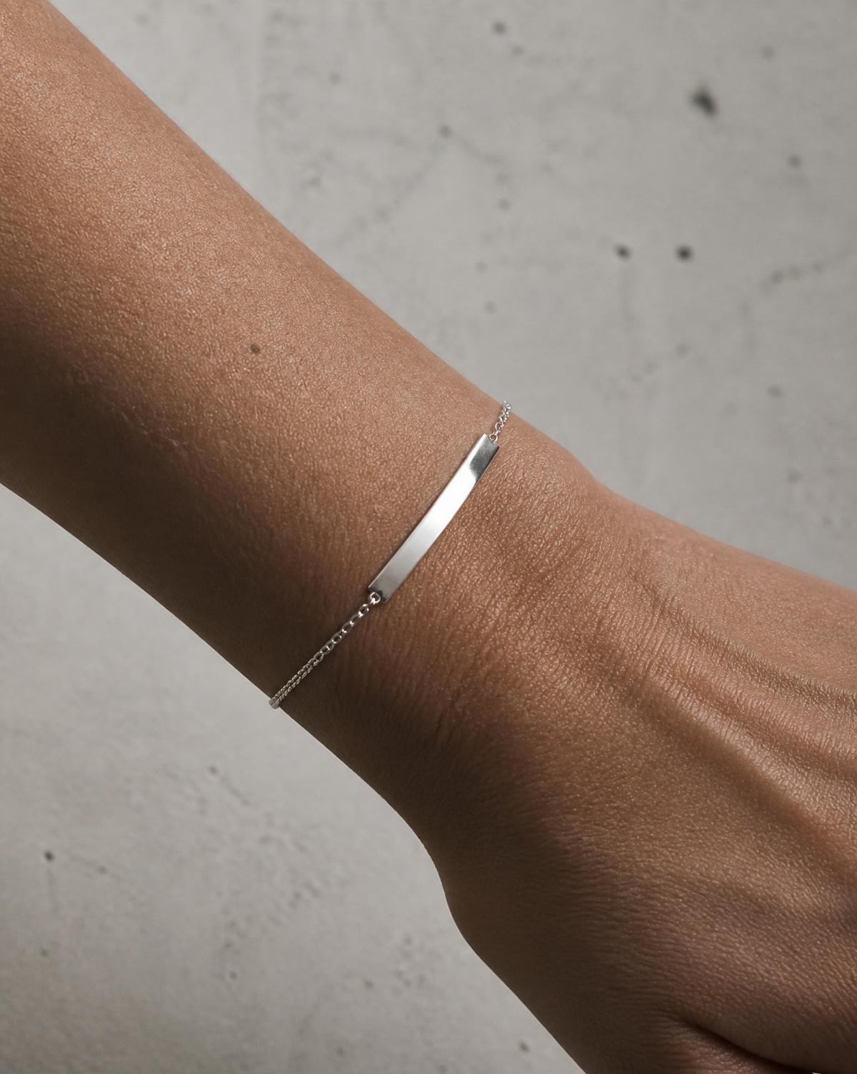 Muñeca con pulsera de plata sobre fondo de concreto