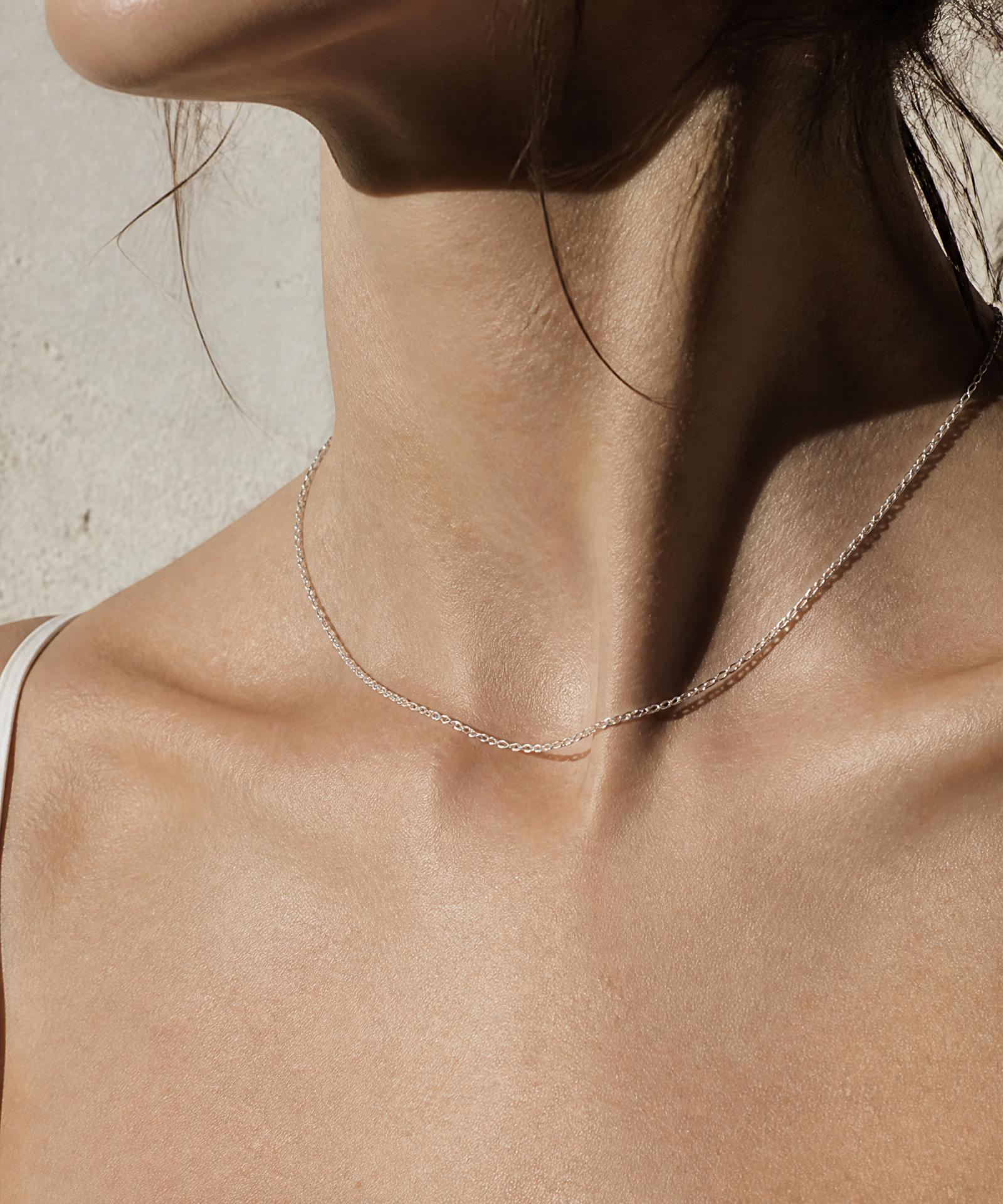Cuello y clavícula con cadena fina de plata, luz natural