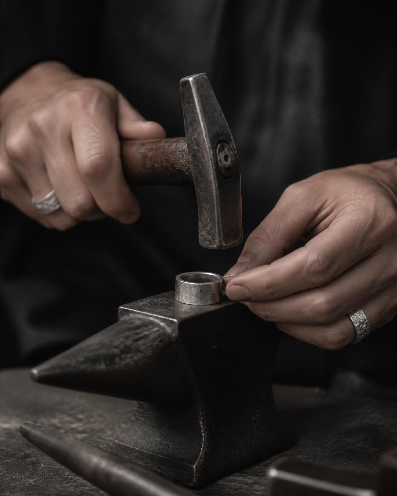 Manos de artesano martillando un anillo de plata